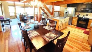 A spacious dining area with a wooden table and chairs, a chandelier, and a kitchen in the background. - Paradise in Island Park! -Best location in Island Park 22 Miles from Yellowstone (Island Park)