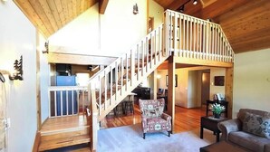 A spacious living area with a wooden staircase leading to an upper level, a cozy seating area with a sofa and armchairs, and a small table with a plant. - Paradise in Island Park! -Best location in Island Park 22 Miles from Yellowstone (Island Park)