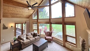 A spacious living room with a high ceiling, large windows, a ceiling fan, and a cozy seating area with a couch and chairs. - Paradise in Island Park! -Best location in Island Park 22 Miles from Yellowstone (Island Park)