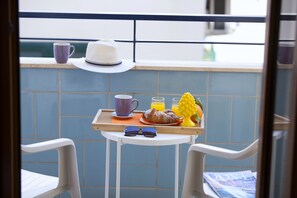 A balcony with a breakfast tray containing croissants, a fruit, a cup, and a glass of orange juice.