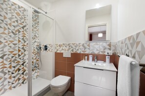A modern bathroom with a shower, toilet, and sink.