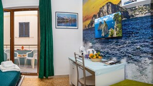 A hotel room with a bed, a desk, a chair, a small table, and a balcony with a view. - B&B Sorrento Mahal Kita with unique style (Sorrento)