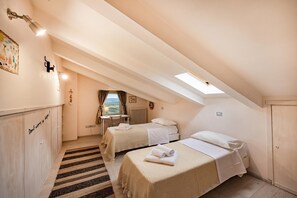 Ein Schlafzimmer mit zwei Betten, einem Fenster, einer Heizung und einem Schreibtisch.