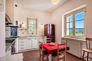 Une cuisine équipée d’une table à manger, de chaises, d’un réfrigérateur, d’une cuisinière et d’une fenêtre donnant sur un paysage agréable.