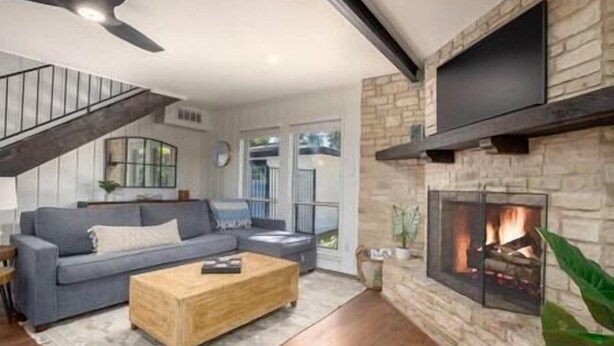 Una sala de estar moderna con chimenea de piedra, un sofá gris y una mesa de centro de madera.