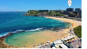 A coastal beach with a clear view of the ocean, beachgoers, and buildings in the background. - 304 Arena Newcastle Beach (Newcastle, New South Wales, Australia)