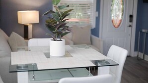 Un comedor moderno con una mesa de vidrio, sillas blancas y una planta en maceta.