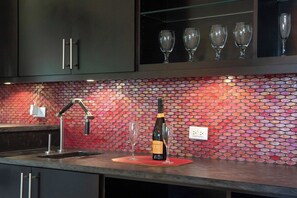 A kitchen with a tiled backsplash, a wine bottle, and two glasses on a mat.