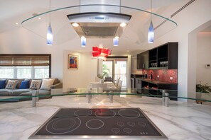 A modern kitchen with a glass-top dining table, a built-in oven, and a bar area with shelves.