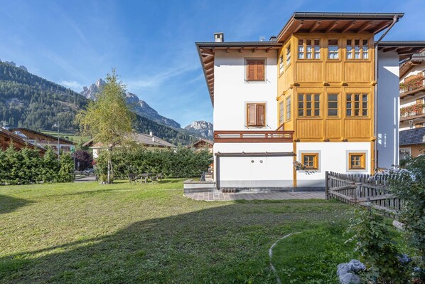 Un bâtiment à deux étages, doté d’une façade blanche et de parties supérieures en bois, qui se détache sur un paysage montagneux.