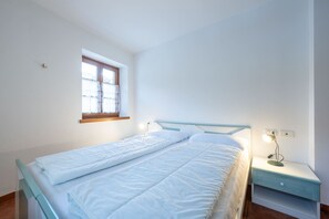 Une chambre à coucher avec un lit, une table de chevet, une lampe et une fenêtre avec des rideaux.