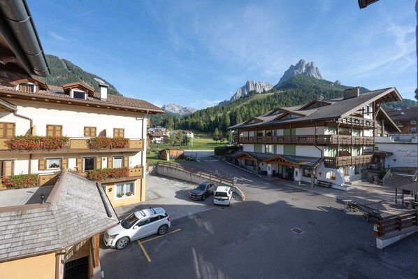 Ein Hotel mit Innenhof, Bergblick und Parkplatz mit Autos.