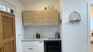 A modern kitchen with wooden cabinets, a built-in oven, and a small shelf with bottles. - Contemporary, Stylish One Bedroom Studio. (Katoomba)