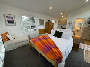 Une chambre à coucher comprenant un lit, une table de chevet, une chaise, une armoire et une salle de bain.