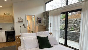 A bedroom with a bed, a nightstand, a desk, and a view of the outdoors. - Contemporary, Stylish One Bedroom Studio. (Katoomba)