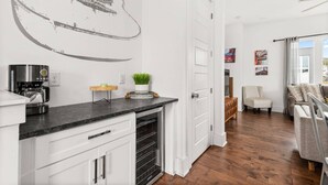 A modern kitchen with white cabinetry, a coffee machine, and a decorative guitar wall art. - V831 ~ East Nashville Charm ~ 11 Beds ~ 4 miles to Downtown and Broadway ~ WiFi ~ Garage Parking (Nashville)