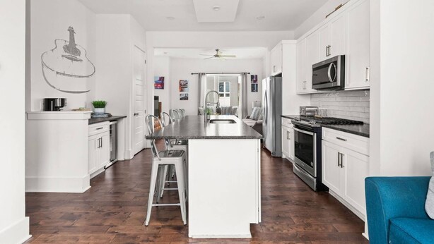 A modern kitchen with white cabinetry, a central island, stainless steel appliances, and a wooden floor. - V831 ~ East Nashville Charm ~ 11 Beds ~ 4 miles to Downtown and Broadway ~ WiFi ~ Garage Parking (Nashville)