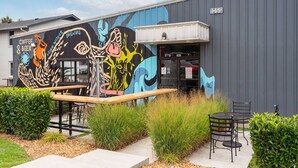 A building with a mural advertising coffee and beer, outdoor seating, and a sign indicating the address 1015G. - V831 ~ East Nashville Charm ~ 11 Beds ~ 4 miles to Downtown and Broadway ~ WiFi ~ Garage Parking (Nashville)