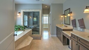 Un baño moderno con lavamanos dobles, ducha con mampara de vidrio y vestidor.