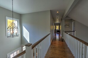 Stunning hallway with a large window, wooden floor, and elegant staircase.