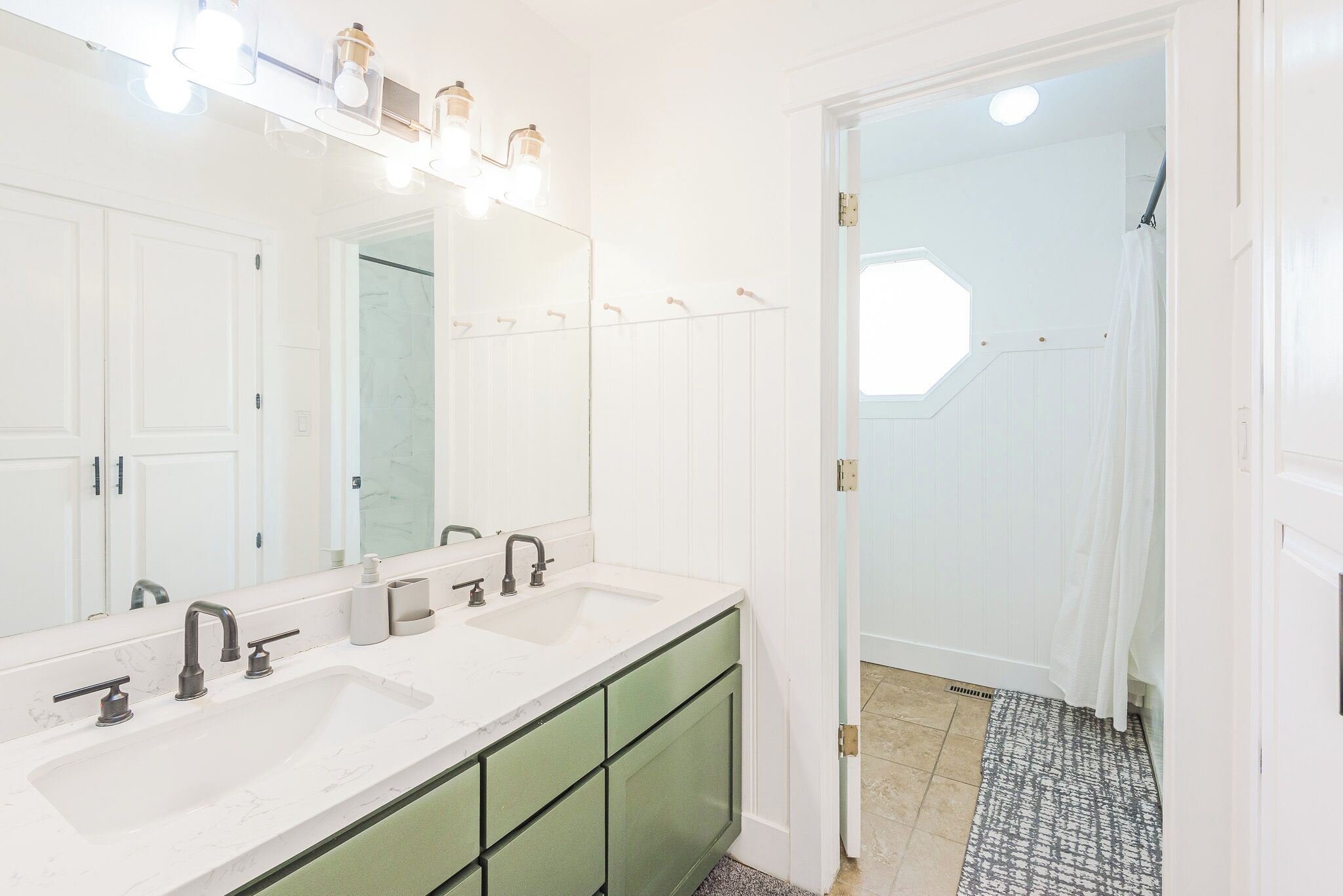 A bathroom with two sinks, a large mirror, and a shower area.