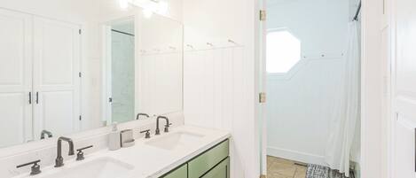 A bathroom with two sinks, a large mirror, and a shower area.