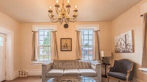 A living room with a tufted sofa, a glass coffee table, a striped armchair, and a chandelier.