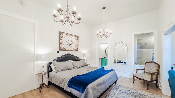 Una camera da letto con un letto grande, due comodini, un lampadario, uno specchio e una sedia.