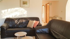 A living room with a black leather sofa, a small wooden table, and a framed picture on the wall.