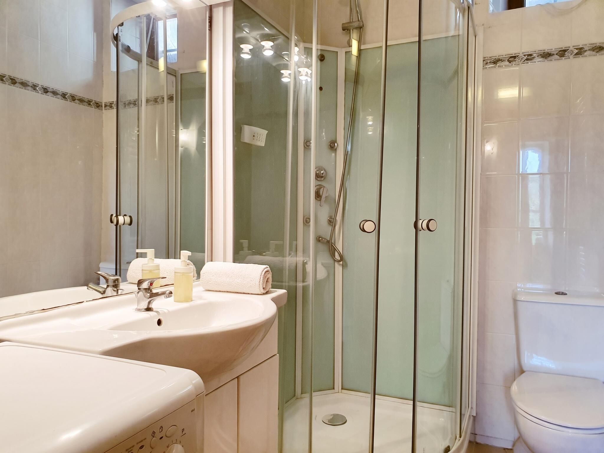 A bathroom with a glass-enclosed shower, a sink with a mirror, and a toilet.