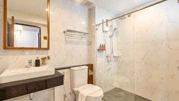 A modern bathroom with a marble backsplash, a black countertop, a white sink, a toilet, and a glass-enclosed shower area.