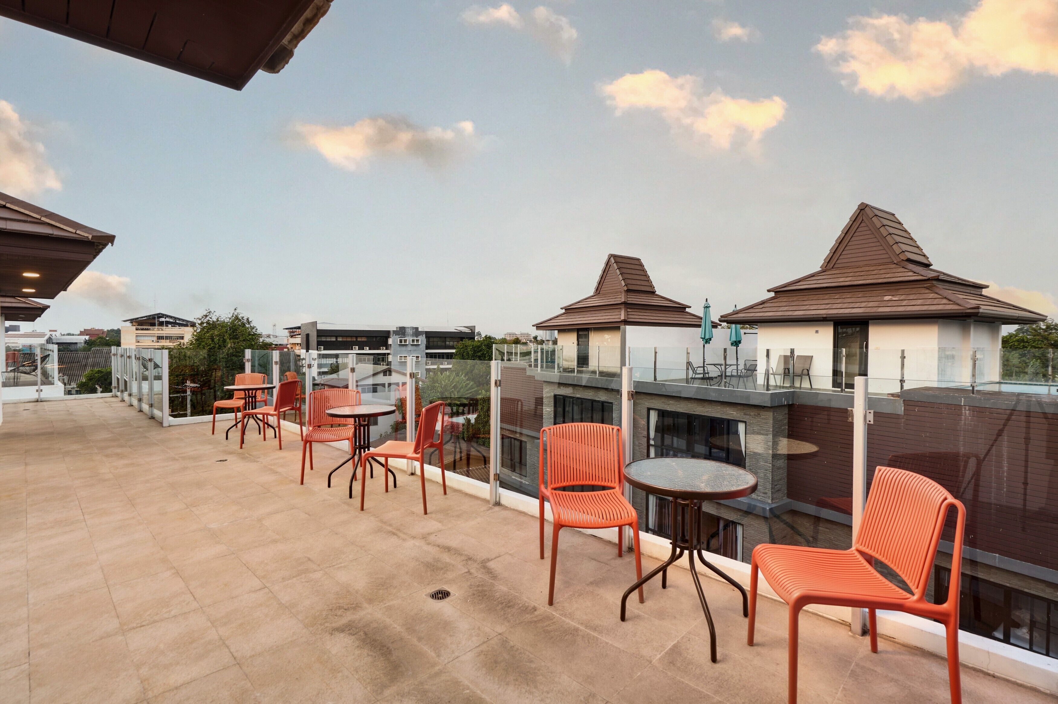 A rooftop terrace with outdoor seating, a view of buildings, and a clear sky.