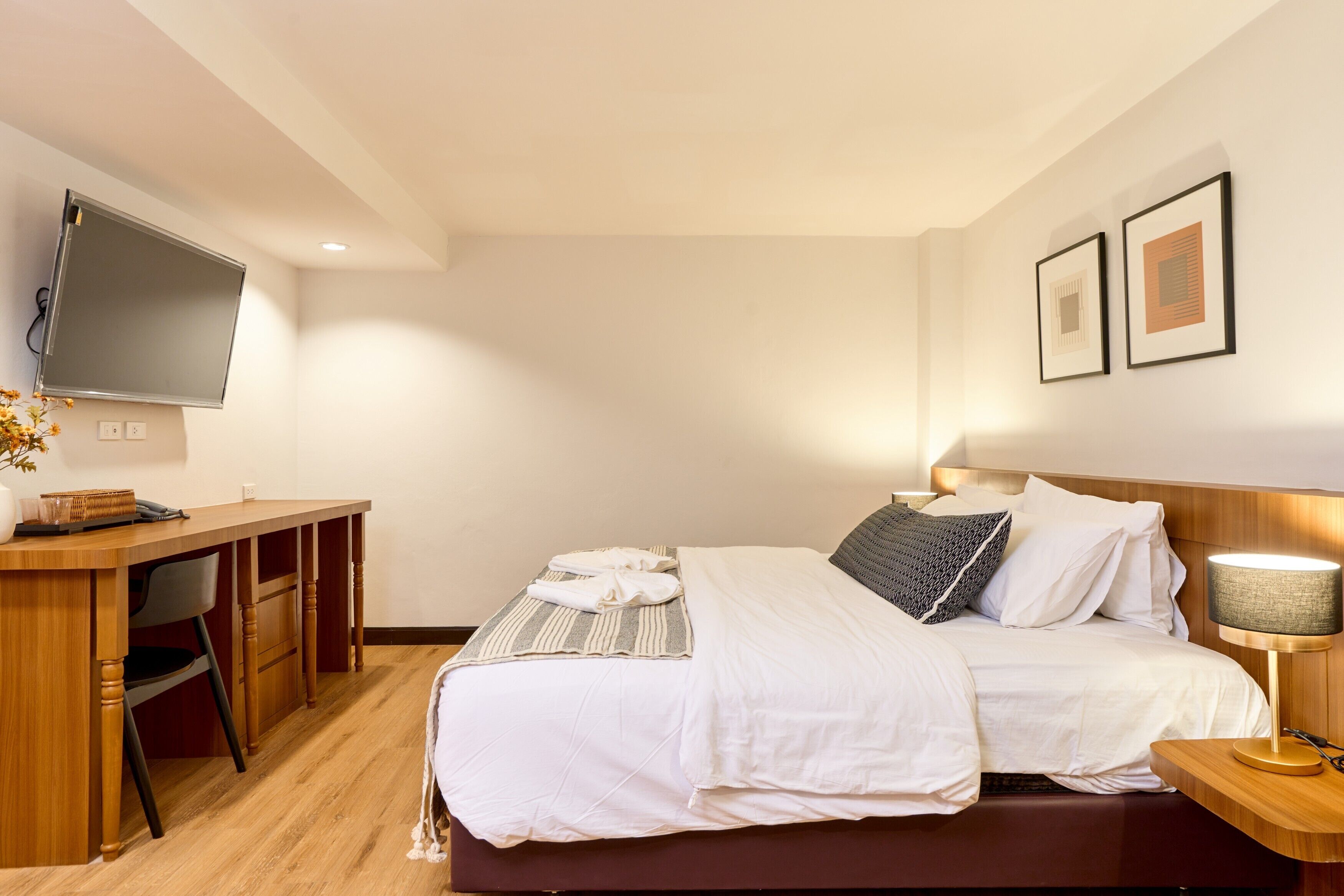 Een hotelkamer met een bed, een bureau, een stoel, een televisie en een lamp.