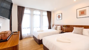 A hotel room with two beds, a flat-screen TV, a desk with a basket, and a window with curtains. - Be Phrasingh Hotel Chiang Mai (Chiang Mai)