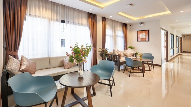 A modern hotel lobby with a sofa, chairs, a table, and a vase of flowers. - Be Phrasingh Hotel Chiang Mai (Chiang Mai)