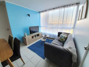 A living room with a TV, sofa, and chairs.