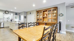 Uma cozinha ampla com armários brancos, uma mesa de jantar de madeira e um aparador embutido.