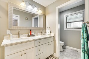 A bathroom with a large mirror, two sinks, a toilet, and a window with blinds. - Lakefront Boating Getaway in Spring City! (Spring City)