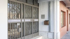 A building facade with a decorative metal gate, a small mailbox, and a set of steps leading to a door. - Live the charms of Seville in Triana (Sevilla)