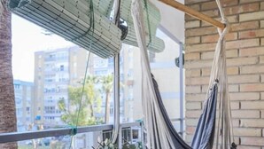 A hammock hanging on a balcony with a view of buildings and greenery. - Live the charms of Seville in Triana (Sevilla)