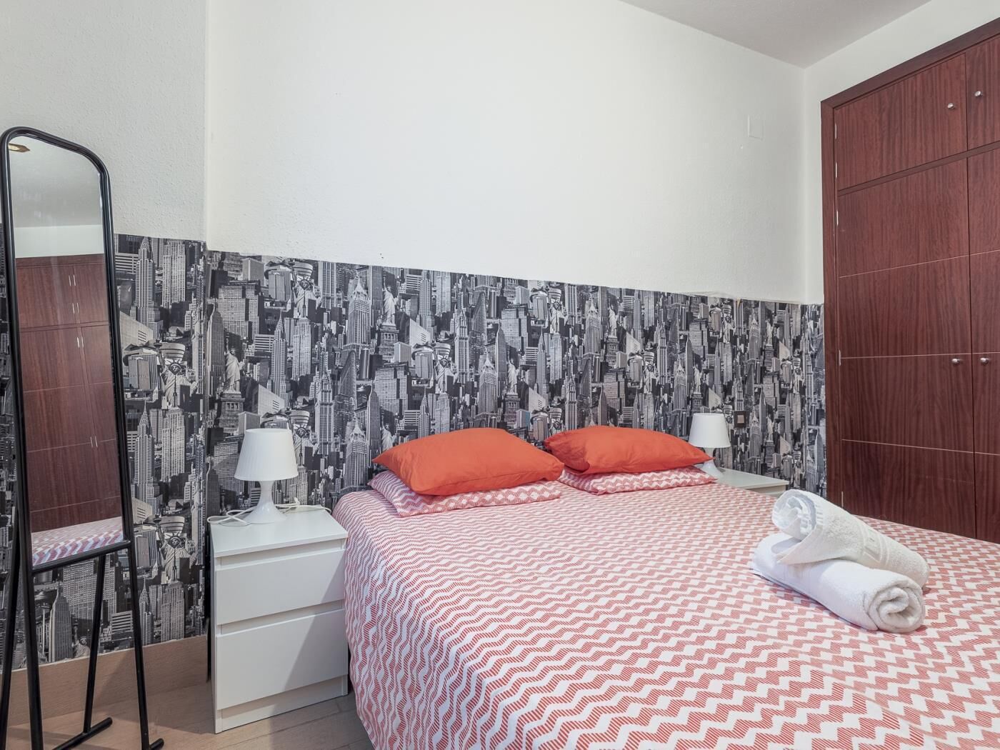 Ein Hotelzimmer mit Bett, Nachttisch, Spiegel und Kleiderschrank.