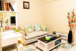 A living room with a sofa, coffee table, and a bookshelf with books and decorative items. - Guoguo Apartment (Shenzhen High-tech Industrial Park) (Shenzhen)