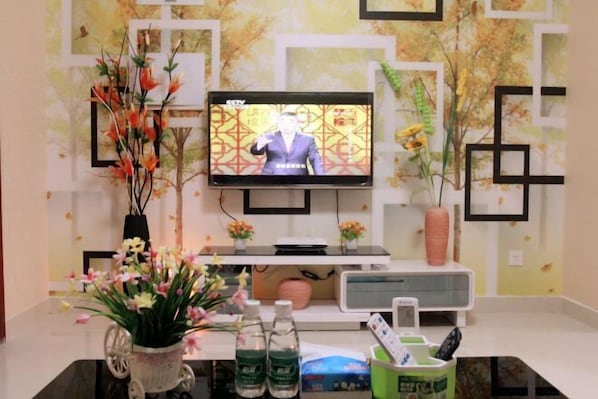 A television mounted on a wall with a floral arrangement in front. - Guoguo Apartment (Shenzhen High-tech Industrial Park) (Shenzhen)