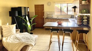 Cocina compacta con comedor, refrigerador, pileta y ventana con persianas.