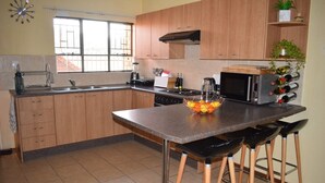 Una cocina con armarios de madera, una isla central con taburetes, un microondas y un fregadero.