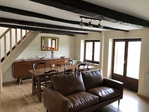 Relax in this spacious living area with a high ceiling, featuring a comfortable sofa and dining table.