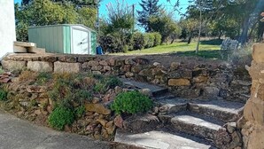 Een stenen trap die naar een huis leidt, met een groene tuinhuisje op de achtergrond.