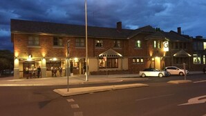 A brick building with multiple windows and a well-lit entrance. - The George Hotel (Bathurst)
