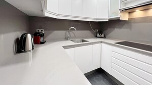 Eine moderne Küche mit weißen Schränken, einer Edelstahl-Spüle und einer eingebauten Dunstabzugshaube.