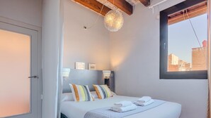 Ein Schlafzimmer mit einem Bett, Nachttischlampen, einem Fenster und einer Tür.